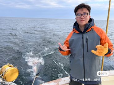 A young angler poses with a catch while fishing offshore, showcasing a large fish being pulled behind the boat.