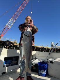 Young angler proudly holding a large Redfish on a boat, showcasing a successful fishing trip.
