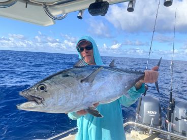Angler proudly displaying a large Tuna while fishing offshore, showcasing the excitement of a successful day on the water.