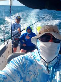 Three anglers enjoying a day on the water, showcasing the comfortable seating and fishing gear on board.
