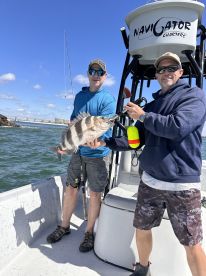 Two anglers proudly displaying a large Snapper while fishing aboard the Navigator Charters boat in a coastal environment.