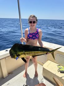 A young angler proudly displaying a vibrant Mahi Mahi while fishing on a sunny day at sea.