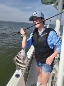 A young angler proudly reeling in a Sheepshead while fishing from a boat, showcasing the excitement of the catch.