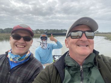 Three anglers enjoying a day on the water, showcasing camaraderie while navigating through a scenic marsh environment.