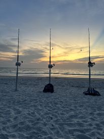 Fishing rods set up on the beach at sunset, creating a serene fishing atmosphere.