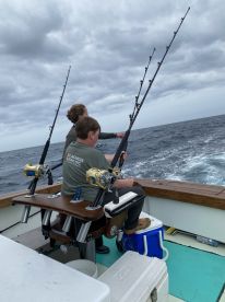 Two young anglers actively fishing from a well-equipped boat, showcasing the excitement of deep-sea fishing in open waters.
