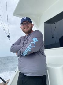 A smiling angler poses inside the boat, showcasing the comfortable seating and fishing environment while preparing for a day on the water.