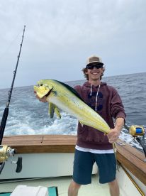 A young angler proudly displaying a vibrant Mahi-Mahi while fishing offshore, showcasing the excitement of a successful catch.