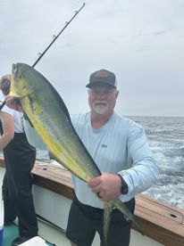 An angler proudly displaying a vibrant Mahi Mahi while fishing offshore, showcasing the excitement of a successful catch.