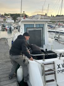 Crew members preparing the boat at a marina during sunset, showcasing the vessel's exterior and surrounding environment.