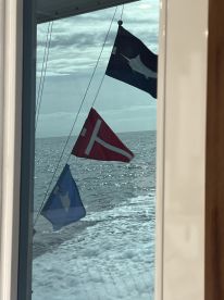 Flags flying from the boat while cruising on open water, showcasing a vibrant maritime atmosphere.