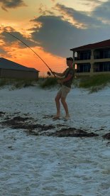 A young angler casting a line at sunset on the beach, showcasing the excitement of surf fishing.