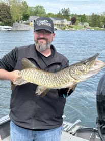 An angler proudly displaying a large Northern Pike while fishing on a scenic lake, showcasing the thrill of freshwater fishing.