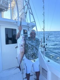 An angler proudly displaying a large Snapper while aboard a fishing charter in open waters.