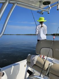 A young angler casting a line from a boat in calm waters, showcasing a serene fishing environment.