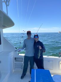 Two anglers proudly displaying their catch of fish while fishing on a boat in open waters.
