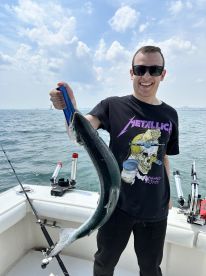 Angler proudly displaying a freshly caught fish while on a boat, enjoying a sunny day on the water.