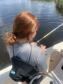 A young angler focused on reeling in a catch while fishing from a boat in calm waters, showcasing the excitement of the fishing experience.