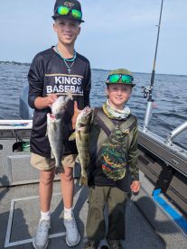 Two young anglers proudly displaying their catch of Walleye while fishing on a lake.