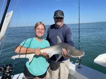 A young angler proudly displaying a caught shark while fishing on a boat, showcasing a successful day on the water.
