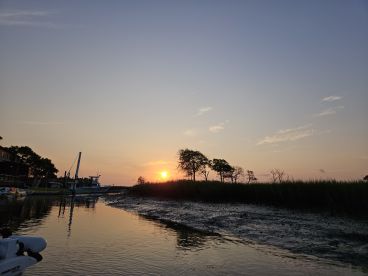 A serene sunset view over the water with a fishing boat docked nearby, showcasing the tranquil fishing environment.