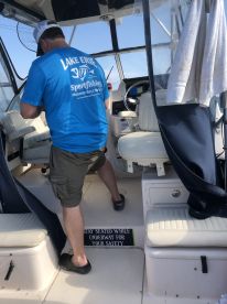 A person is seen inside a fishing boat, preparing for the trip, with a focus on the helm and seating area. The boat is equipped for sportfishing on Lake Erie.