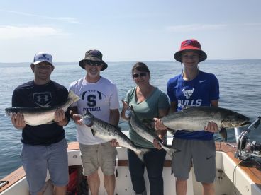 A family group proudly displaying their catch of Salmon while enjoying a sunny day on the water.