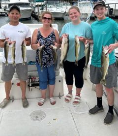 A group of four anglers proudly displaying their catch of Walleye on a fishing charter, showcasing a successful day on the water.