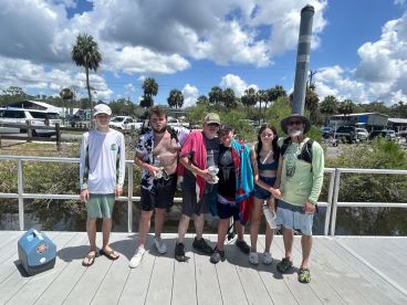 A group of anglers posing together on the dock after a successful fishing trip, showcasing their catch in a vibrant outdoor setting.