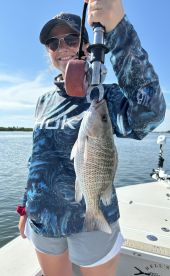 An angler proudly displaying a freshly caught fish while fishing on a boat, showcasing a beautiful day on the water.