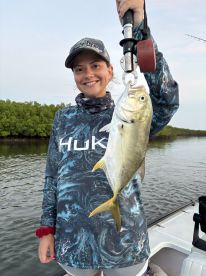 A young angler proudly displaying a Yellowtail Snapper caught during a fishing trip in a mangrove area.