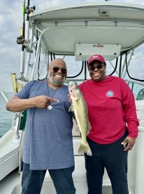 Two anglers proudly displaying a caught Walleye aboard a fishing boat, showcasing a successful day on the water.