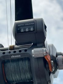 Close-up of a fishing reel featuring a depth counter, showcasing essential fishing equipment for deep-sea angling.