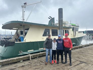 A group of young anglers posing in front of the fishing charter boat 'El Dorado' at the marina, showcasing the boat's exterior.