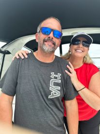 A couple enjoying their time aboard a fishing boat, smiling and posing for a photo in the cabin area.