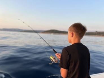 A young angler casting a line while fishing on a calm sea, showcasing the excitement of the sport.