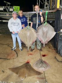 A group of anglers proudly displaying their catch of stingrays after a night fishing trip, showcasing the excitement of a successful outing.