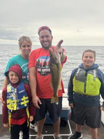 A family proudly displays a large Walleye caught during their fishing trip on Lake Superior, showcasing a fun day on the water.