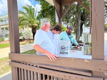 Three individuals at a cleaning station, preparing freshly caught fish near a waterfront setting, showcasing a family-friendly fishing experience.