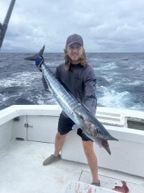 Angler proudly displaying a large Wahoo while fishing offshore, showcasing the excitement of a successful catch.