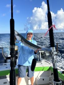 An angler proudly displaying a large Barracuda while fishing offshore, showcasing the excitement of a successful catch.