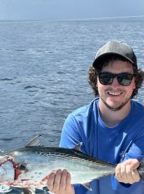 Angler proudly displaying a freshly caught fish while out on the open water, showcasing a successful day of fishing.