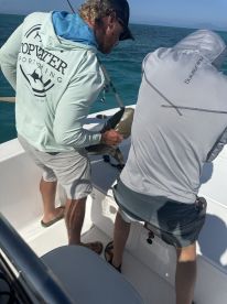 Two anglers actively preparing to fish on a boat, showcasing a vibrant fishing environment in clear blue waters.