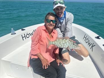 A proud moment on the boat as an angler holds up a beautiful Grouper caught during a sunny fishing trip.
