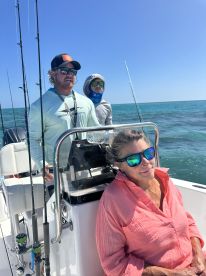 A group of anglers enjoying a day on the water, with one person seated at the helm and two others in the background, showcasing a comfortable boat interior.