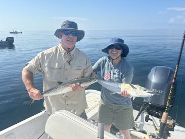 Two anglers proudly displaying their catches of Spanish Mackerel while fishing on a calm day in the Gulf of Mexico.