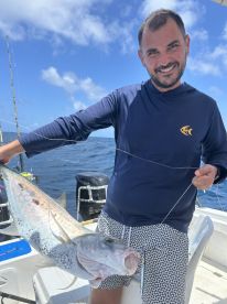 An angler proudly displaying a large fish while out on the open water, showcasing a successful day of fishing.