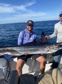 Anglers proudly displaying a large Mahi Mahi while fishing offshore, showcasing a successful day on the water.