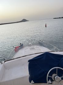 View from the front of a boat, showcasing the calm waters and distant island during a sunset fishing trip.