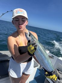 A young angler proudly displaying a large fish while fishing on a boat in clear blue waters.